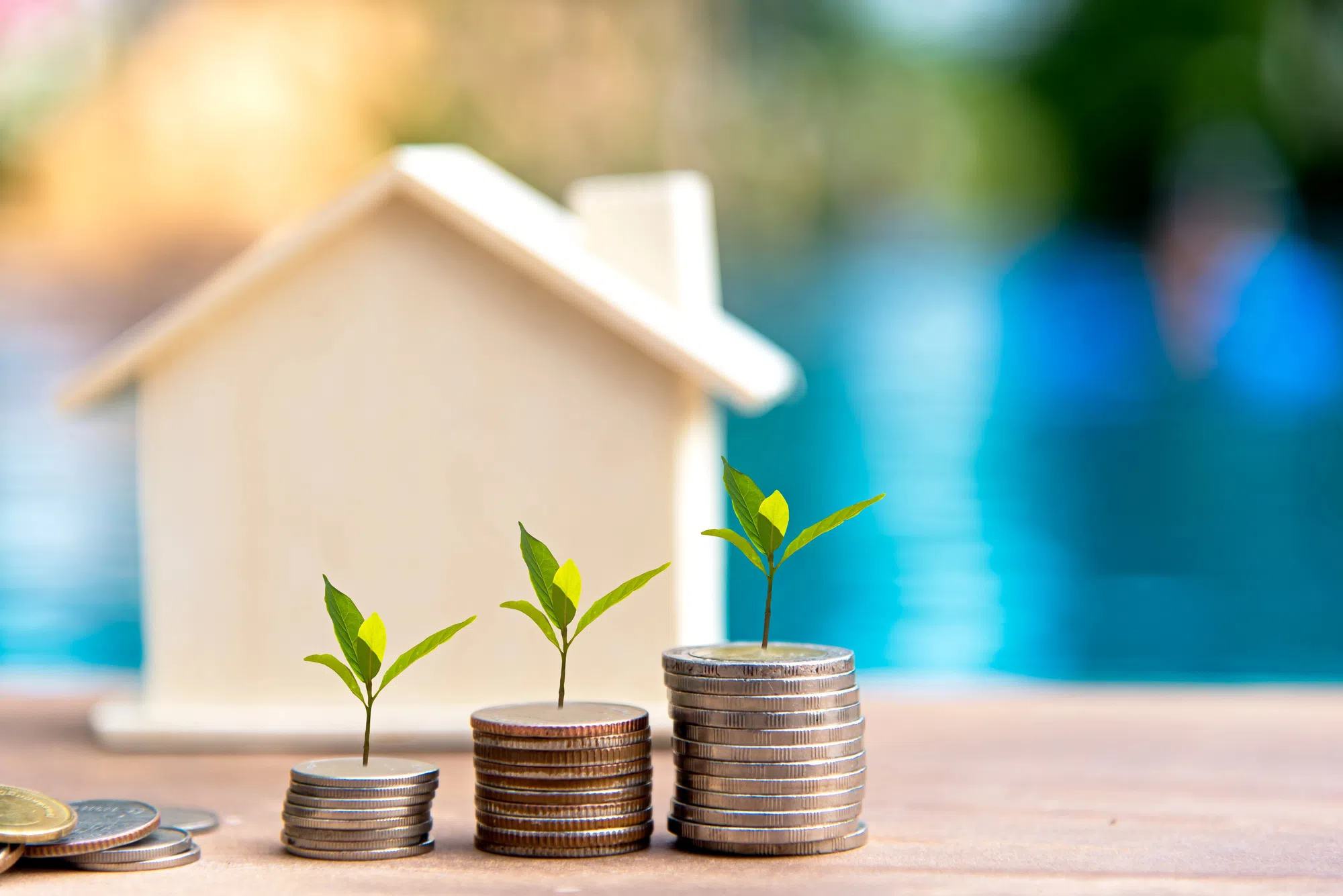 Miniaturhaus auf Münzstapeln als Symbol für Immobilien-Wertentwicklung