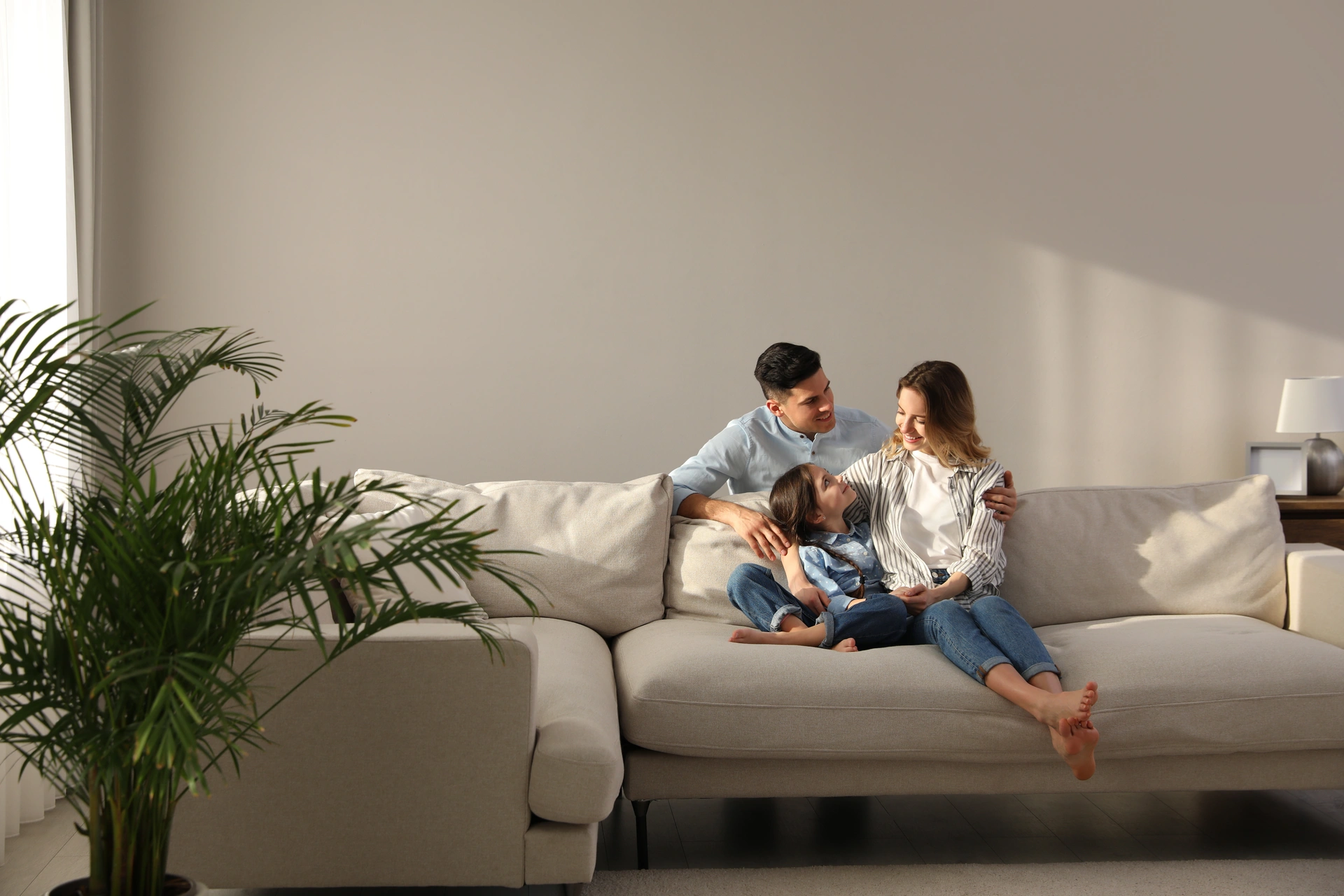 Familie mit Kind und Hund auf einem Sofa im Wohnzimmer