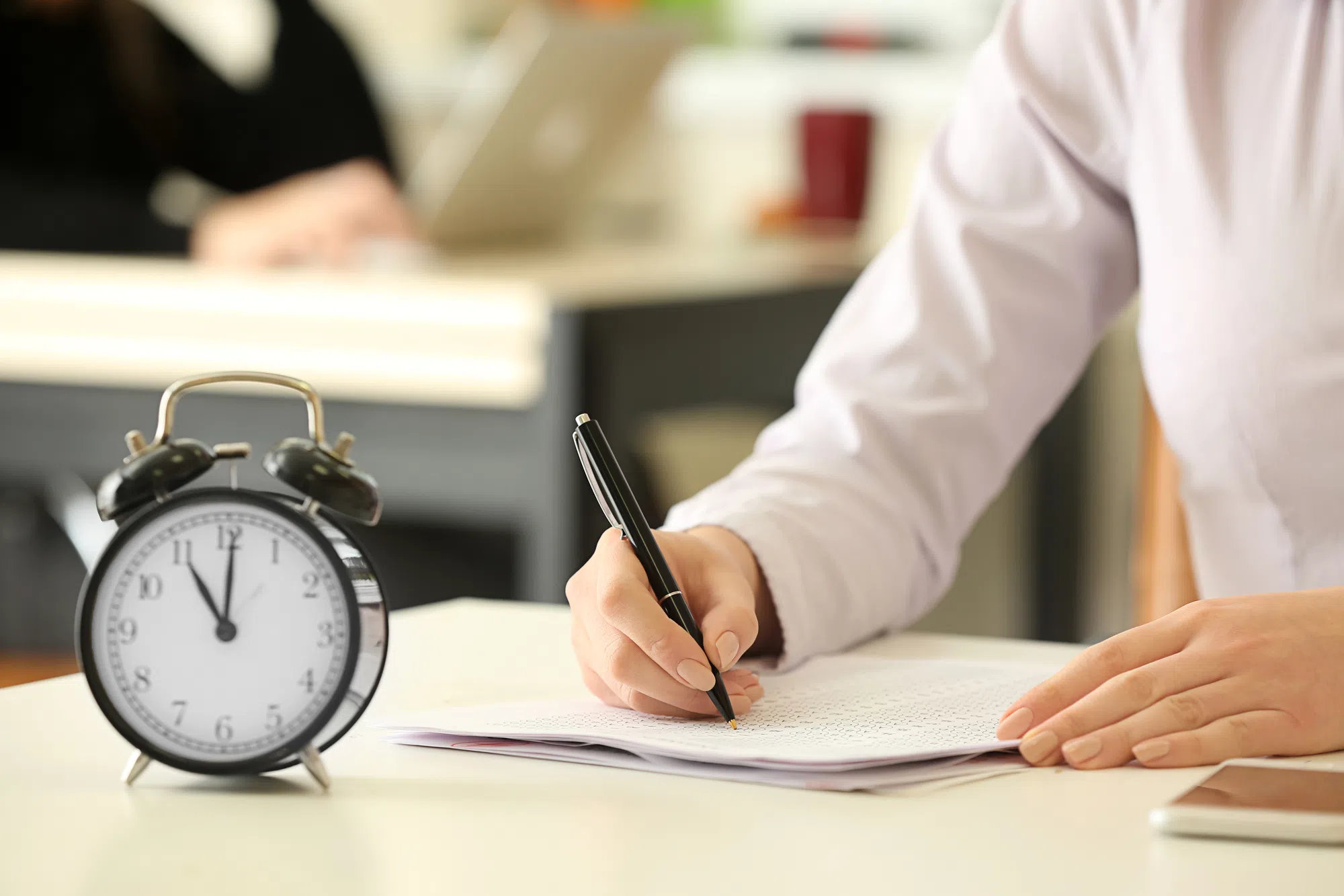 Hausmodell mit Uhr als Motiv für den richtigen Investitionszeitpunkt
